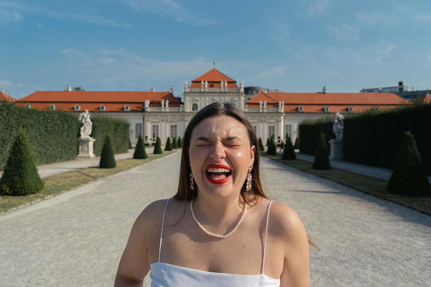 A joyful moment in front of a palatial building with terracotta roofs and manicured gardens.
