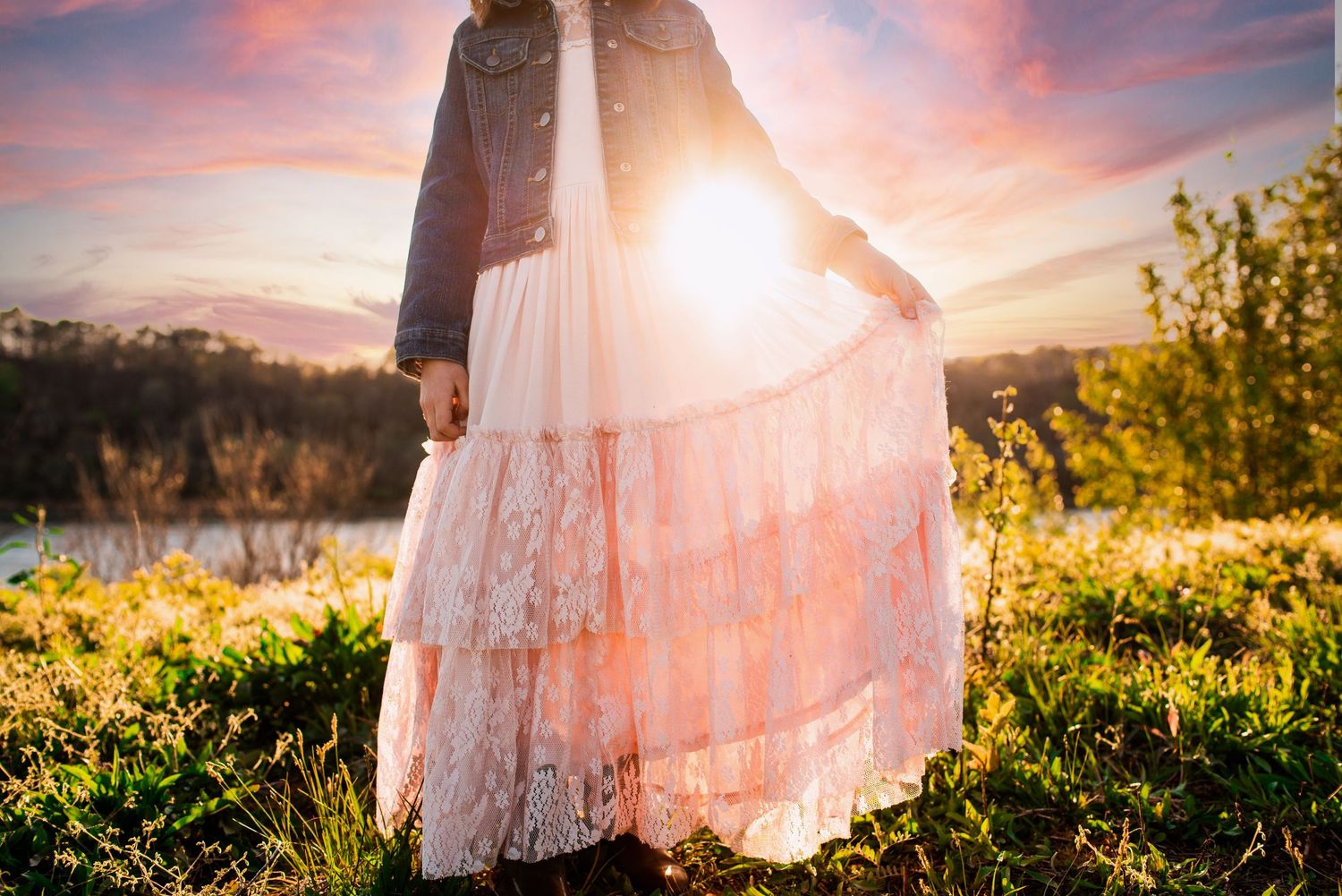 A girl in a pink dress and jean jacket with the sun coming through