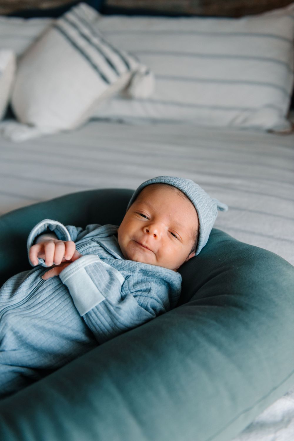 Peaceful sleeping baby wearing soft blue clothing on cozy bedding.
