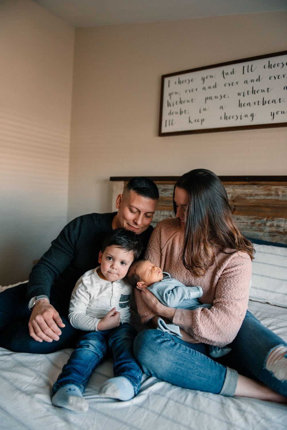 Intimate family portrait showing playful interaction on white bedding.