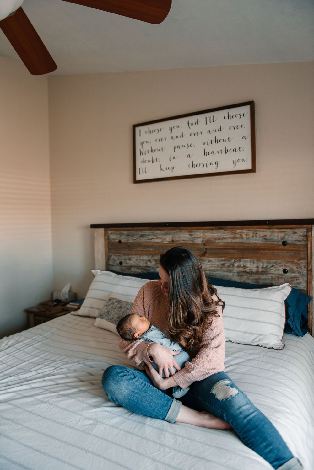 Family sharing intimate moments together on bed with rustic wooden headboard and wall art.