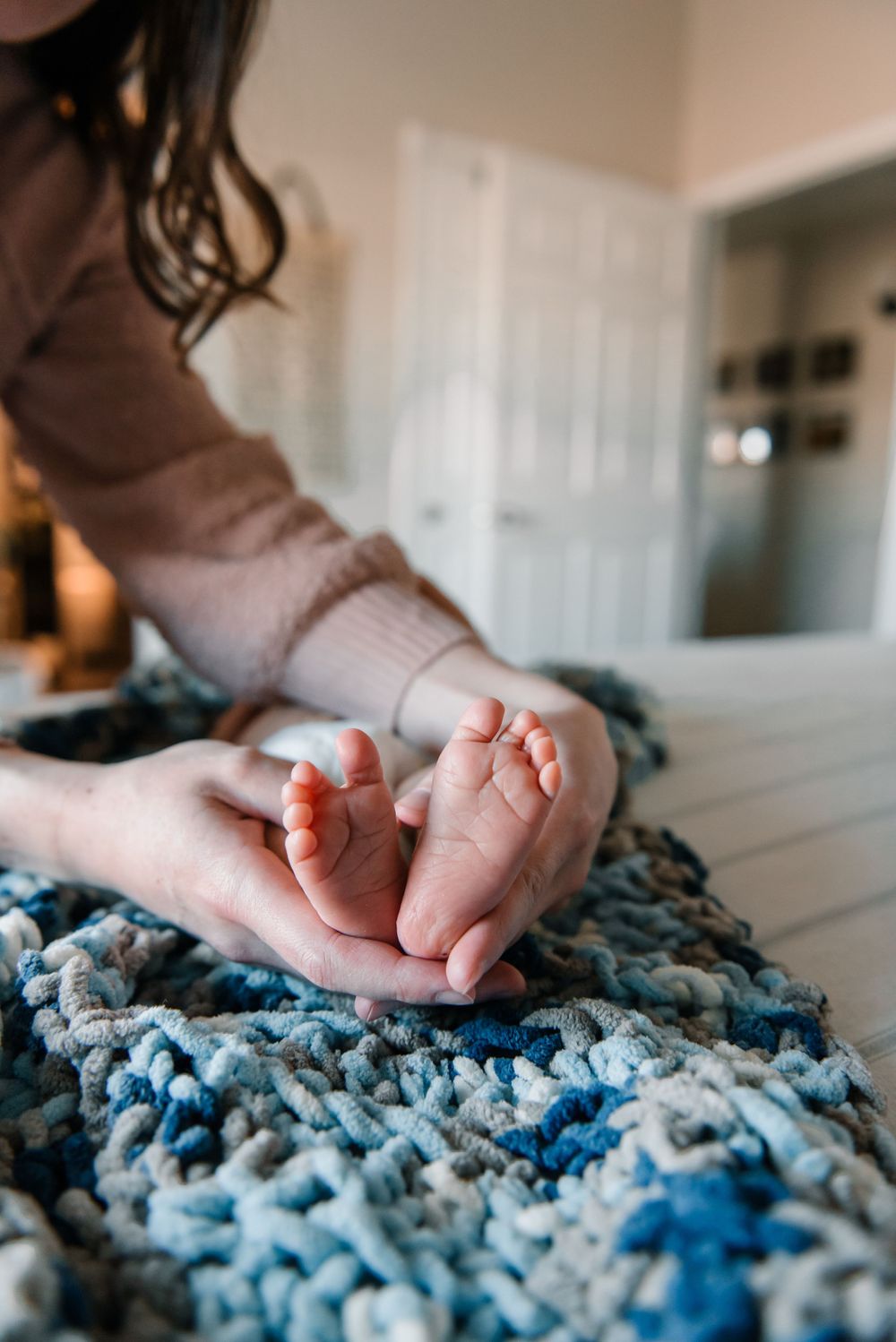 Delicate newborn feet against a textured blue and white knit blanket.