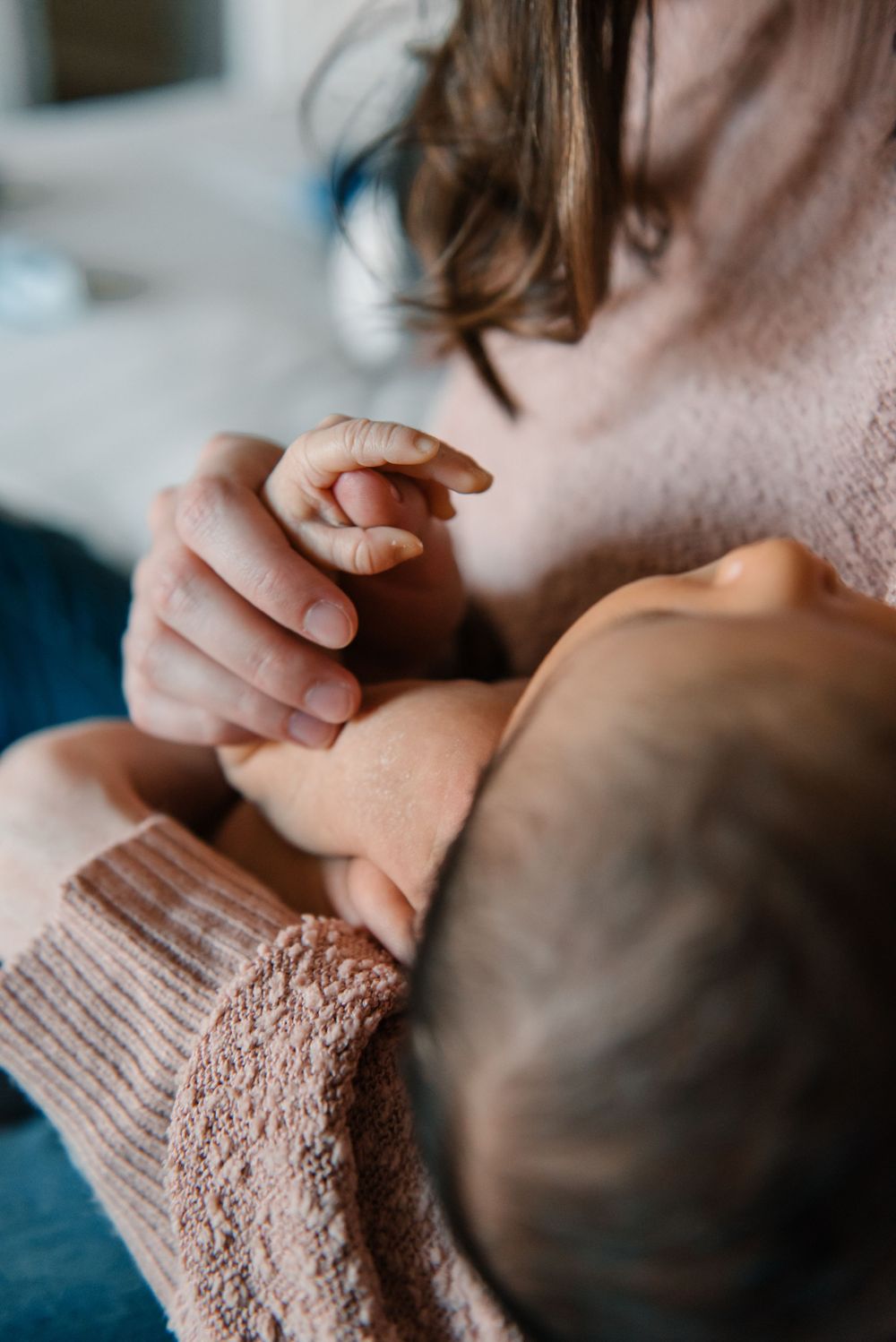 Tender parenting moment with newborn baby in soft pink sweater.
