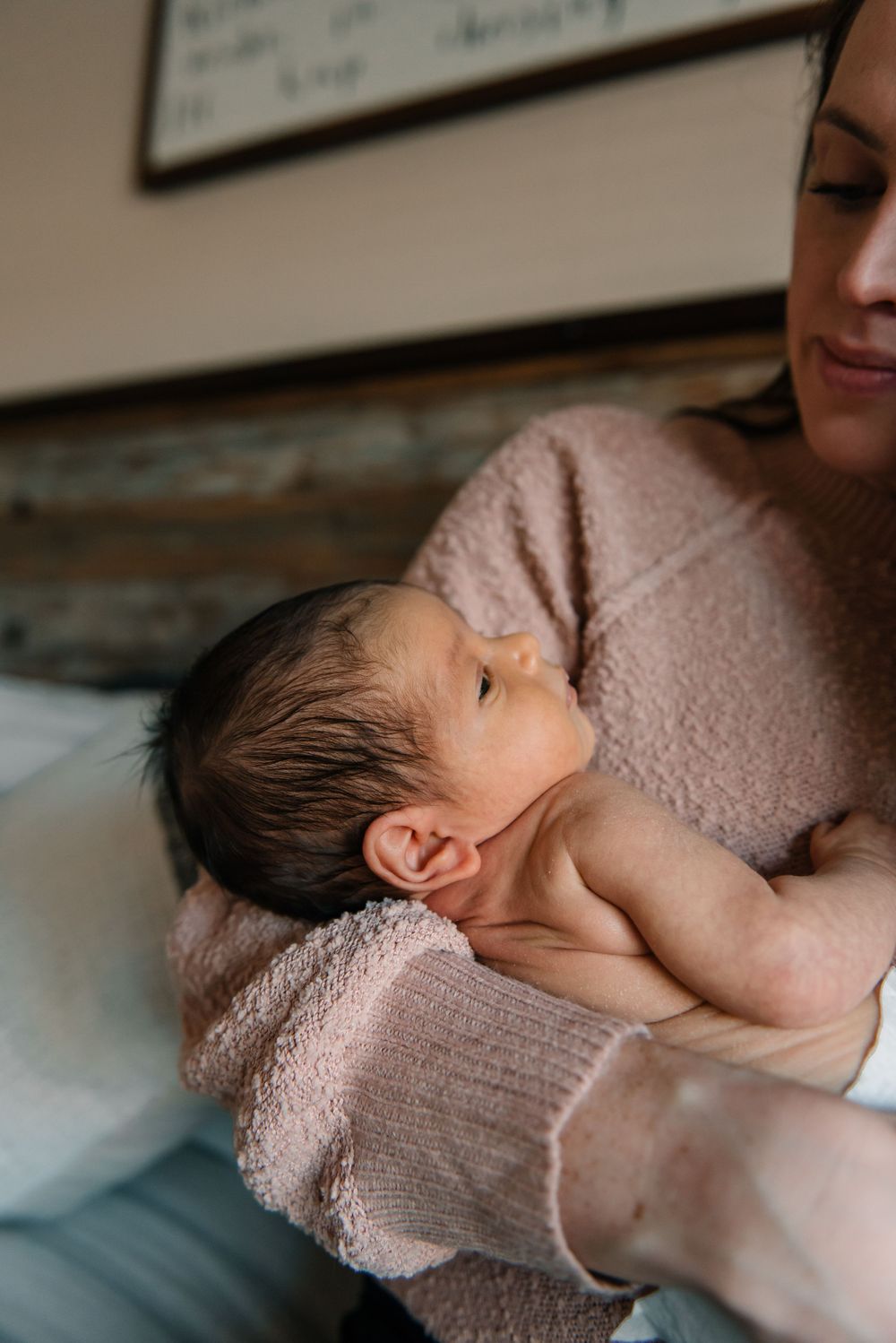 Peaceful newborn resting against parent wearing soft pink knit sweater.