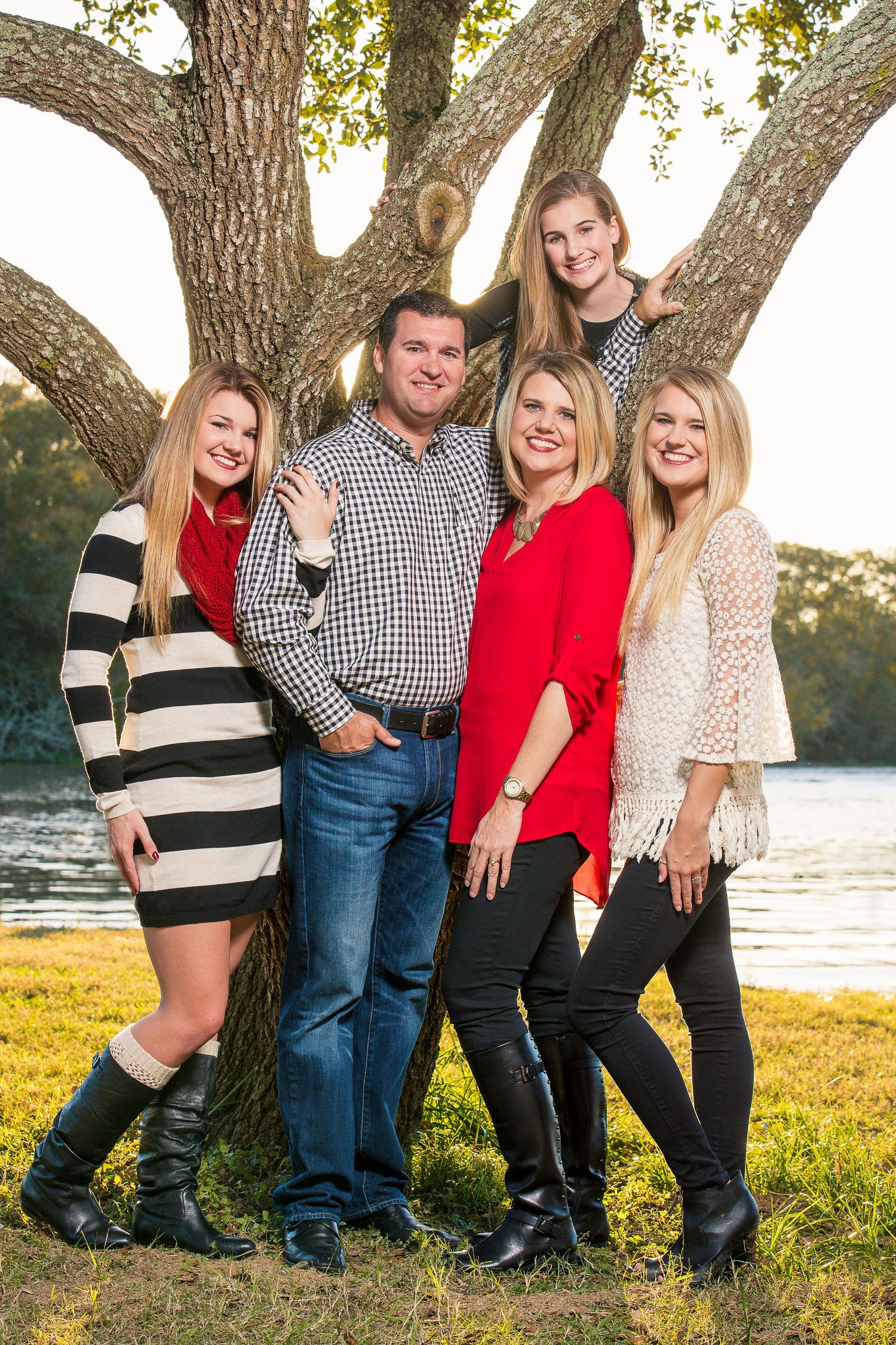 Family group portrait under large oak tree by waterfront.