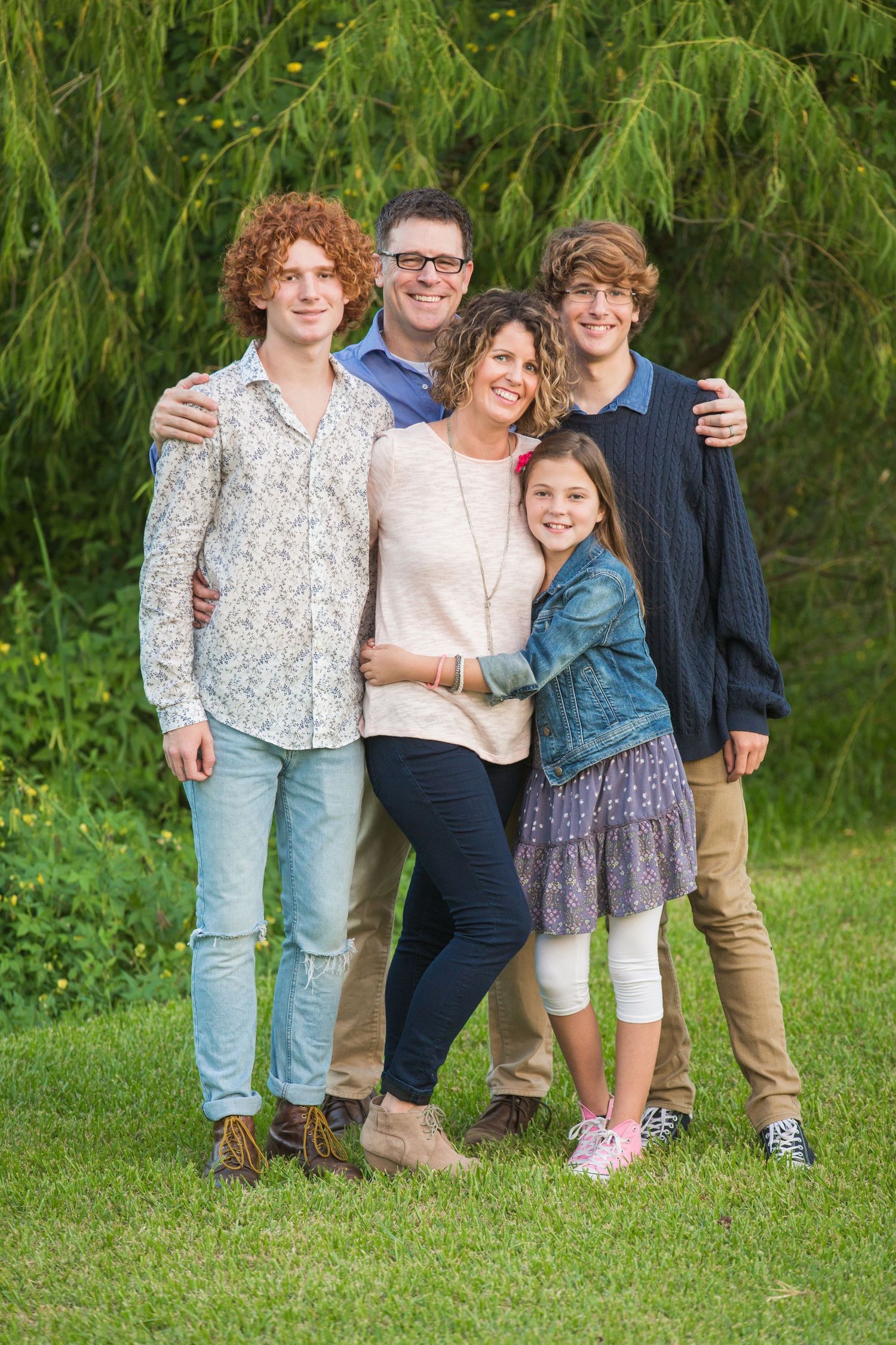 A group portrait on grass with casual clothing and natural smiles.