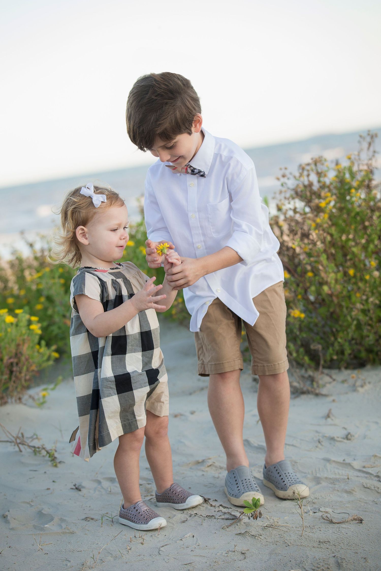 A tender moment between parent and child exploring on a sandy beach.