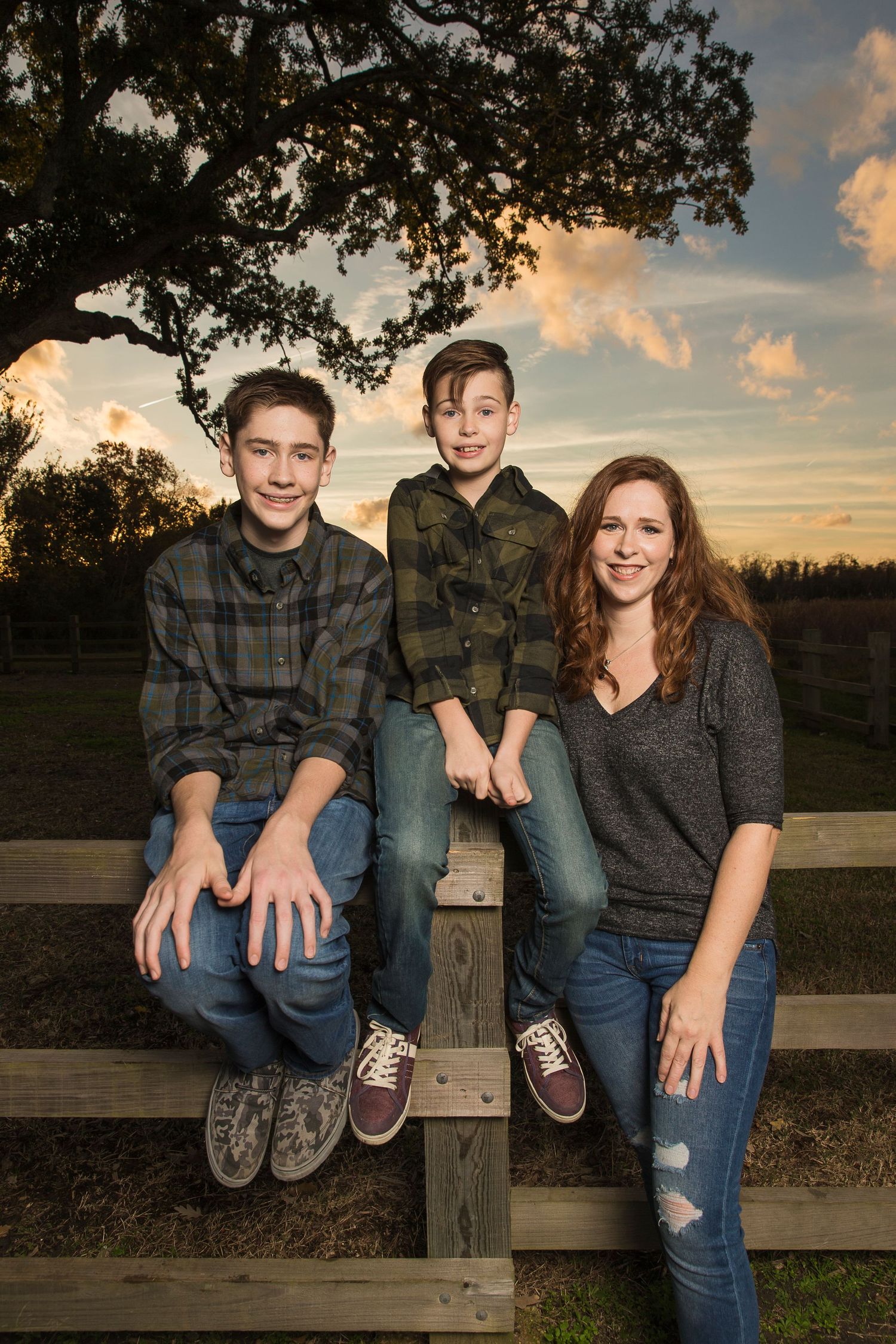Casual family portraits taken on a wooden fence at sunset.
