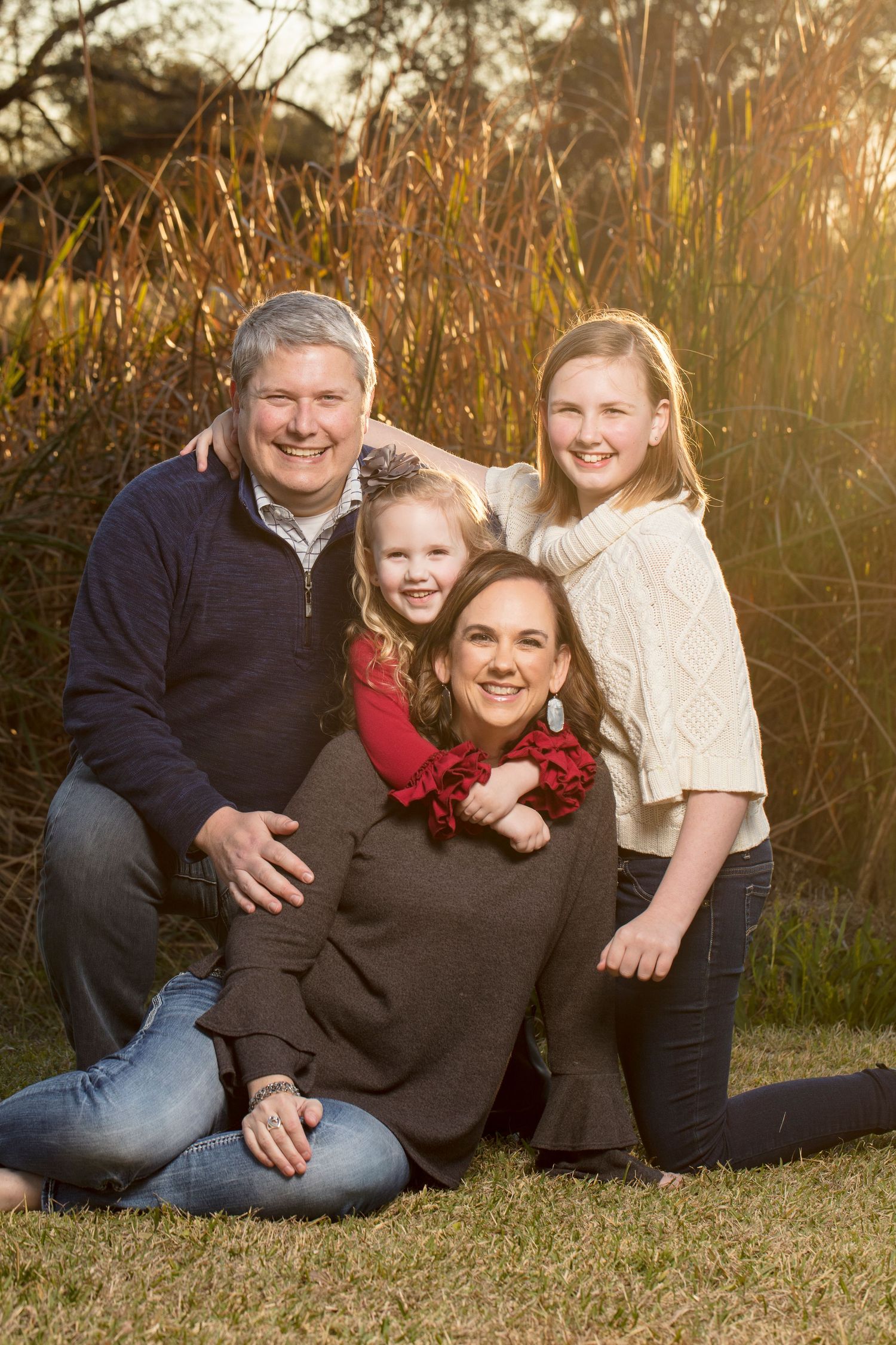 Family portrait session at sunset in tall grass with warm golden lighting.