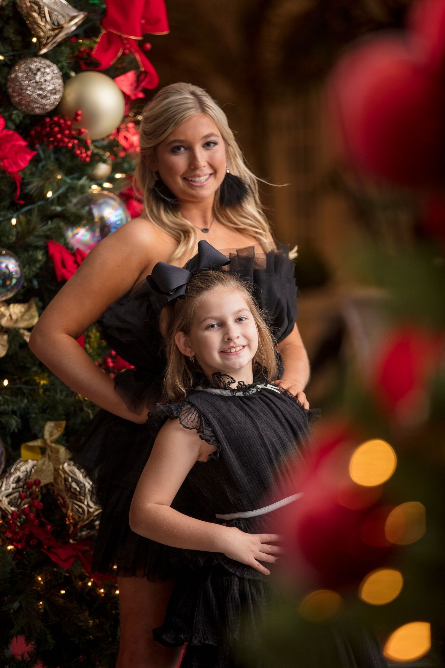 Holiday portrait with decorated Christmas tree and bokeh lights in the background.