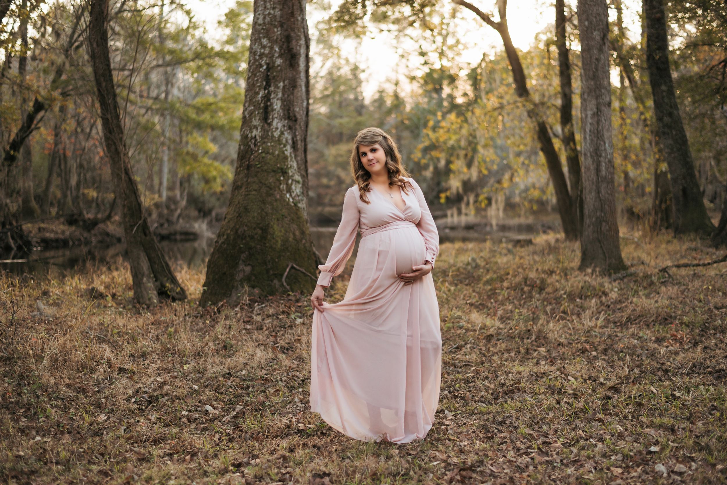 Professional outdoor photography session in a wooded area with warm autumn lighting.