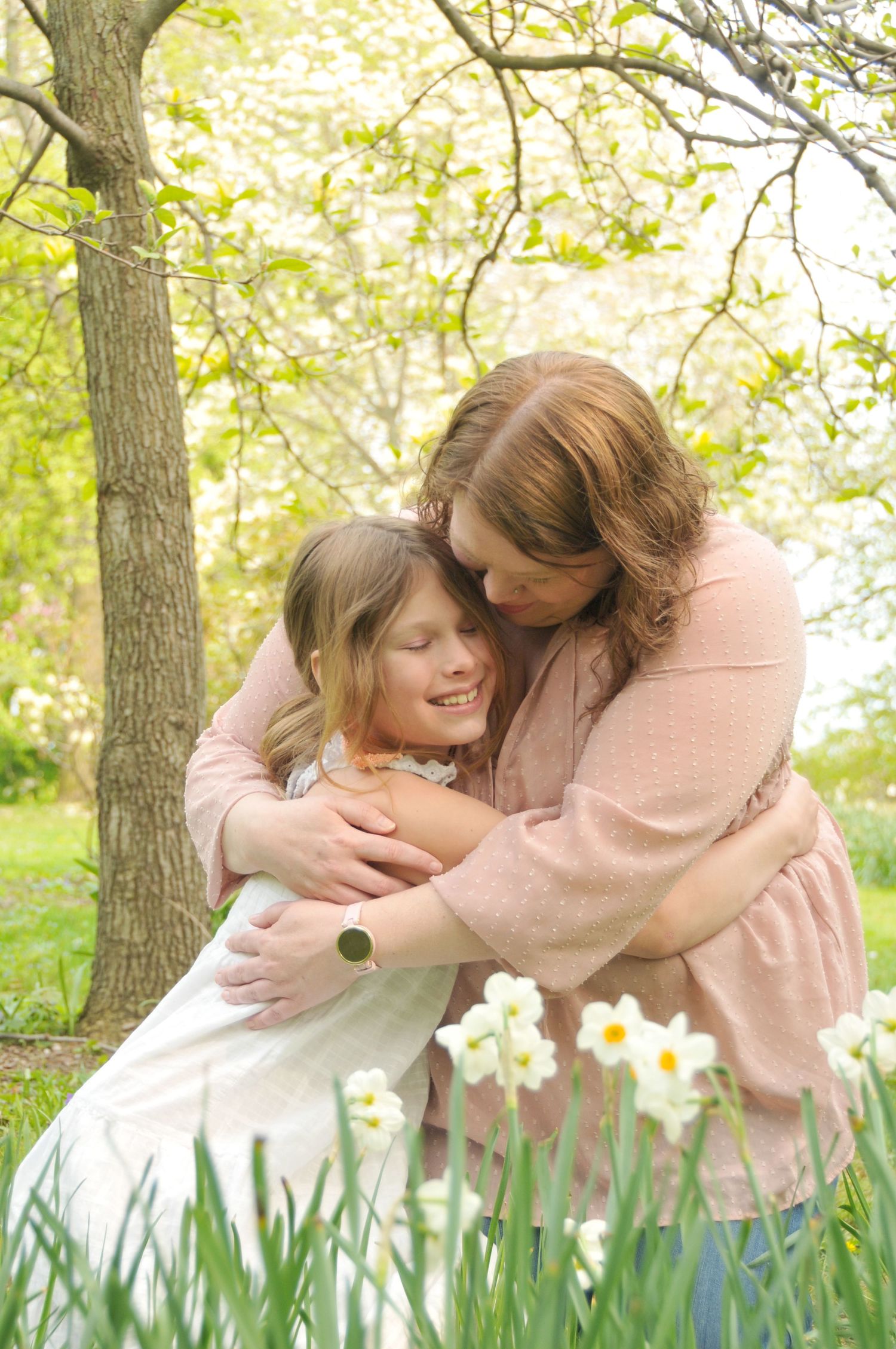 Photo of mom and daughter hugging with daffodils