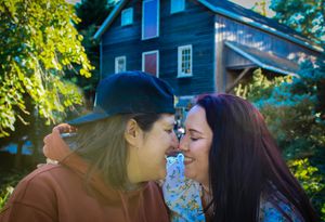 Intimate moment between two people sharing a close moment in front of a blue house.