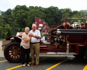 A vintage red fire truck is displayed with the historic mill building visible in the background.