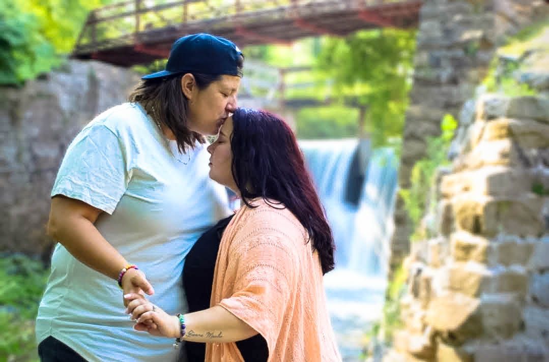 A romantic moment between two people sharing an intimate embrace by a scenic waterfall.
