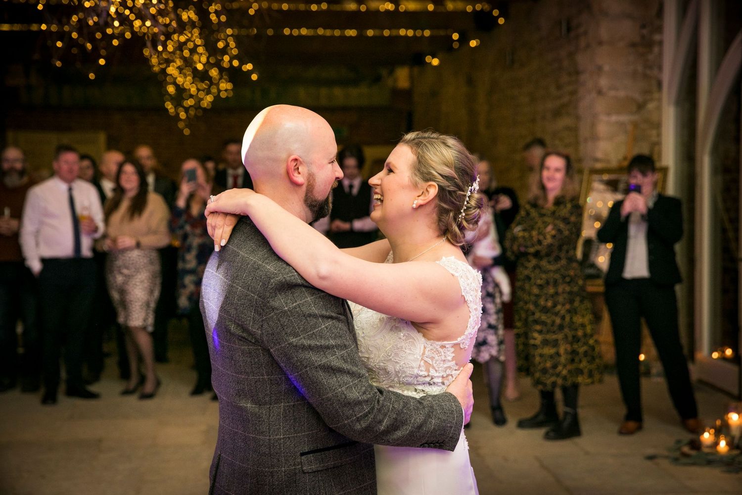 Evening wedding reception with couples dancing under warm string lights.