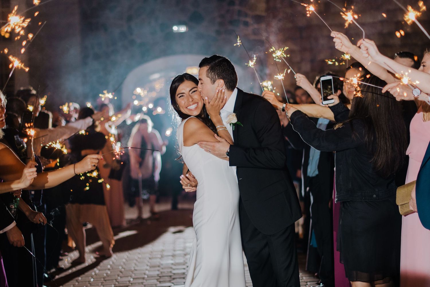 Newlywed couple dances beneath a magical sparkler sendoff at their evening wedding reception.