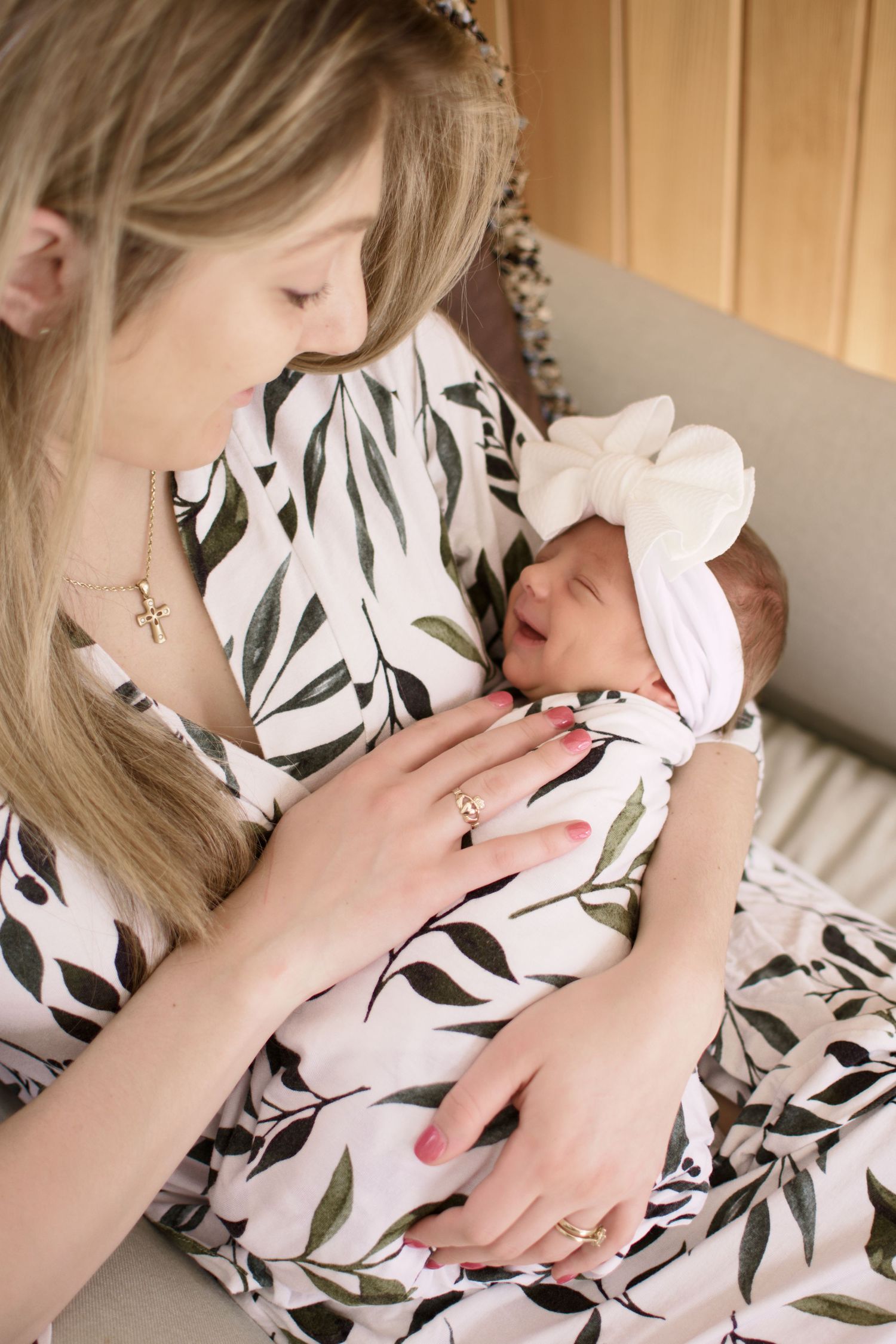 A person in a floral dress holds and nurtures a small baby.