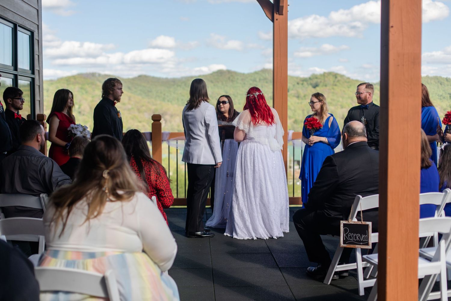 Wedding guests gathered for outdoor ceremony with mountain views in background.