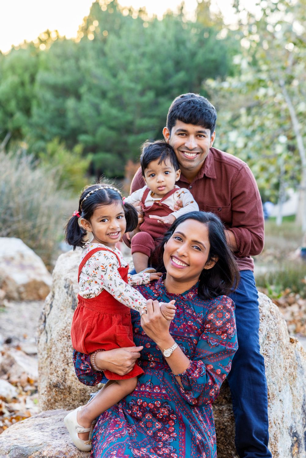 Orange County photographer captures  family of four with two young children smiling together on rocky outdoor terrain.
