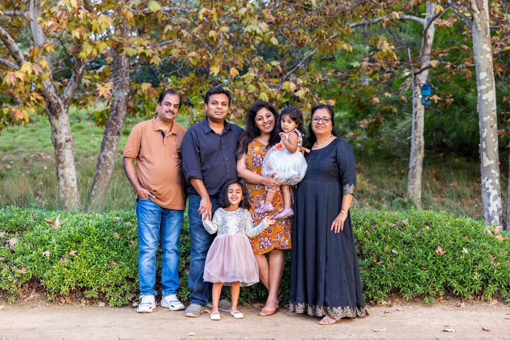Orange County photographer captures  Indian family posing outdoors among trees and greenery for a portrait session.