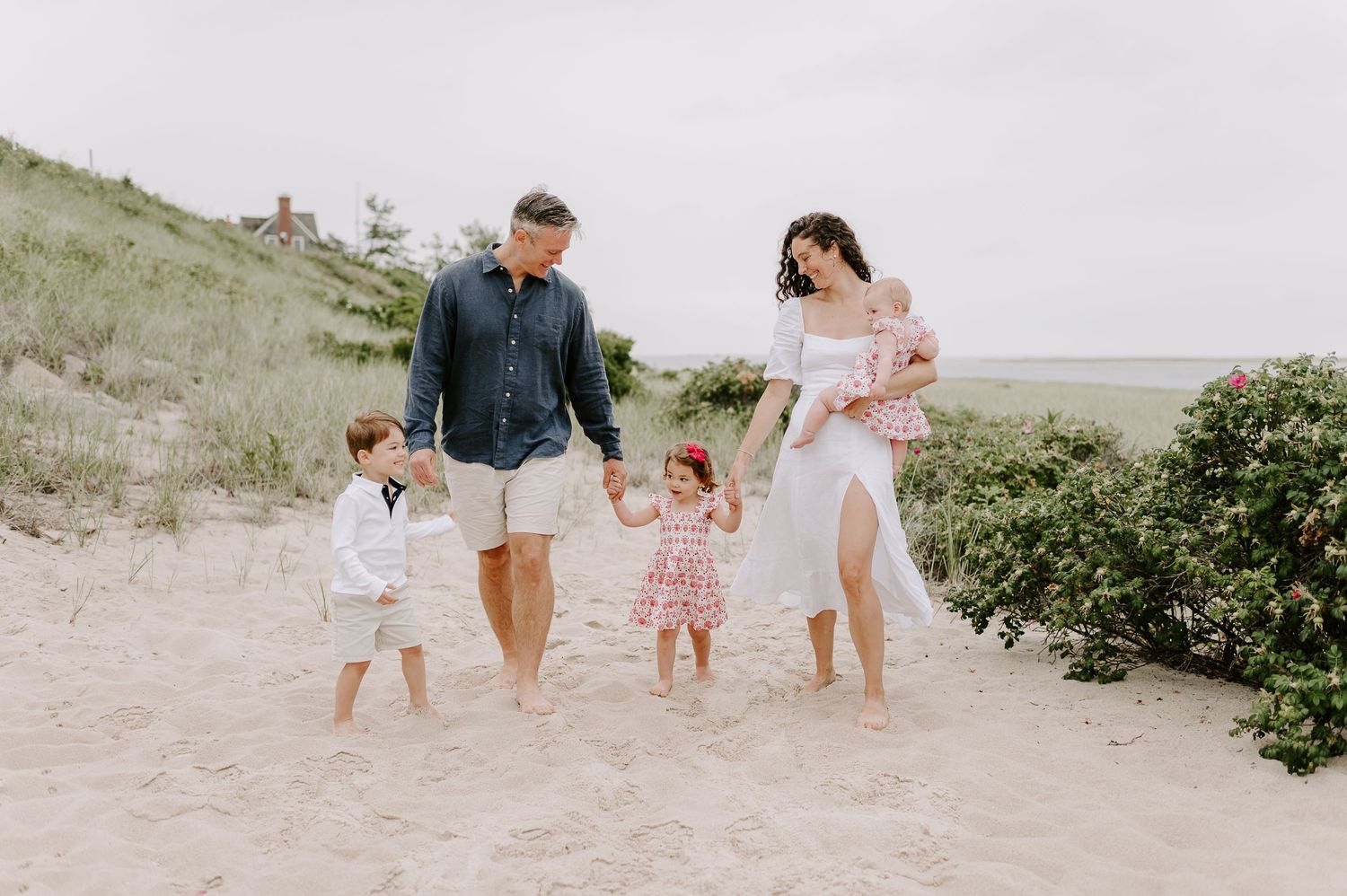 Family walking together on a sandy beach path during sunset.