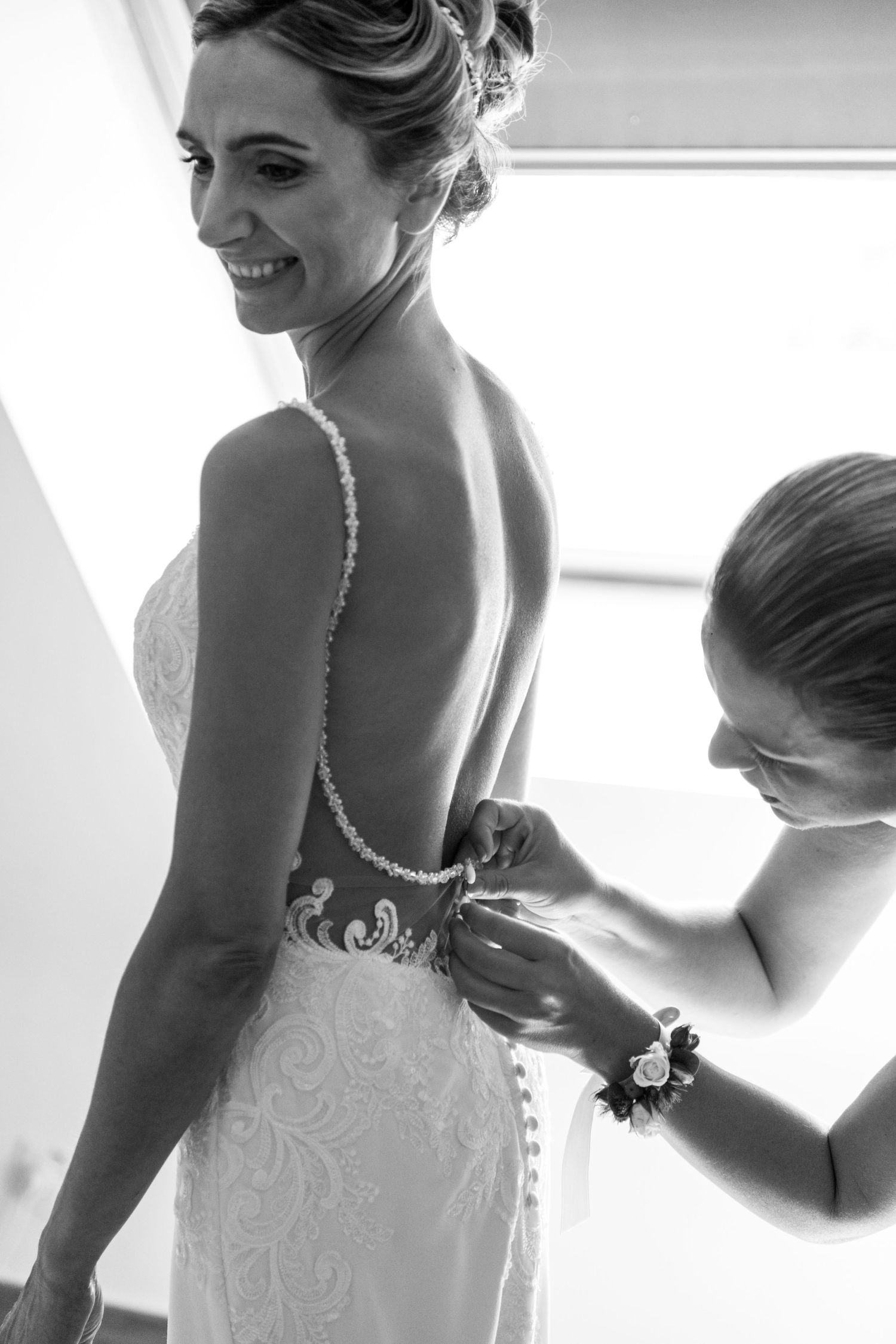 mariée qui se fait mettre sa robe par sa demoiselle d'honneur