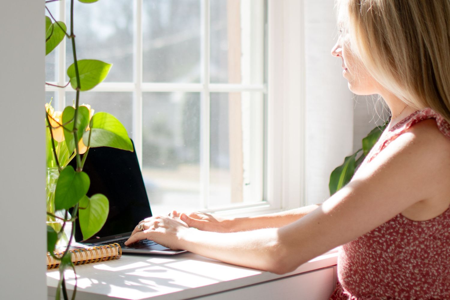 Lauren May enjoys respond to client inquiries surrounded by direct light in her home office.