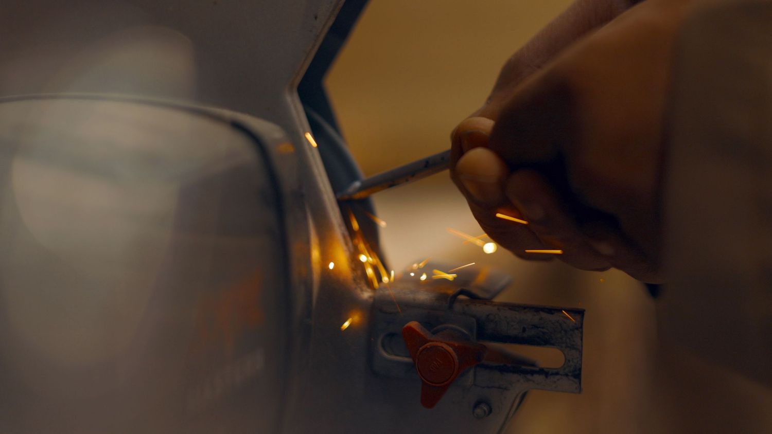 Close-up of hands working on mechanical parts in warm lighting.