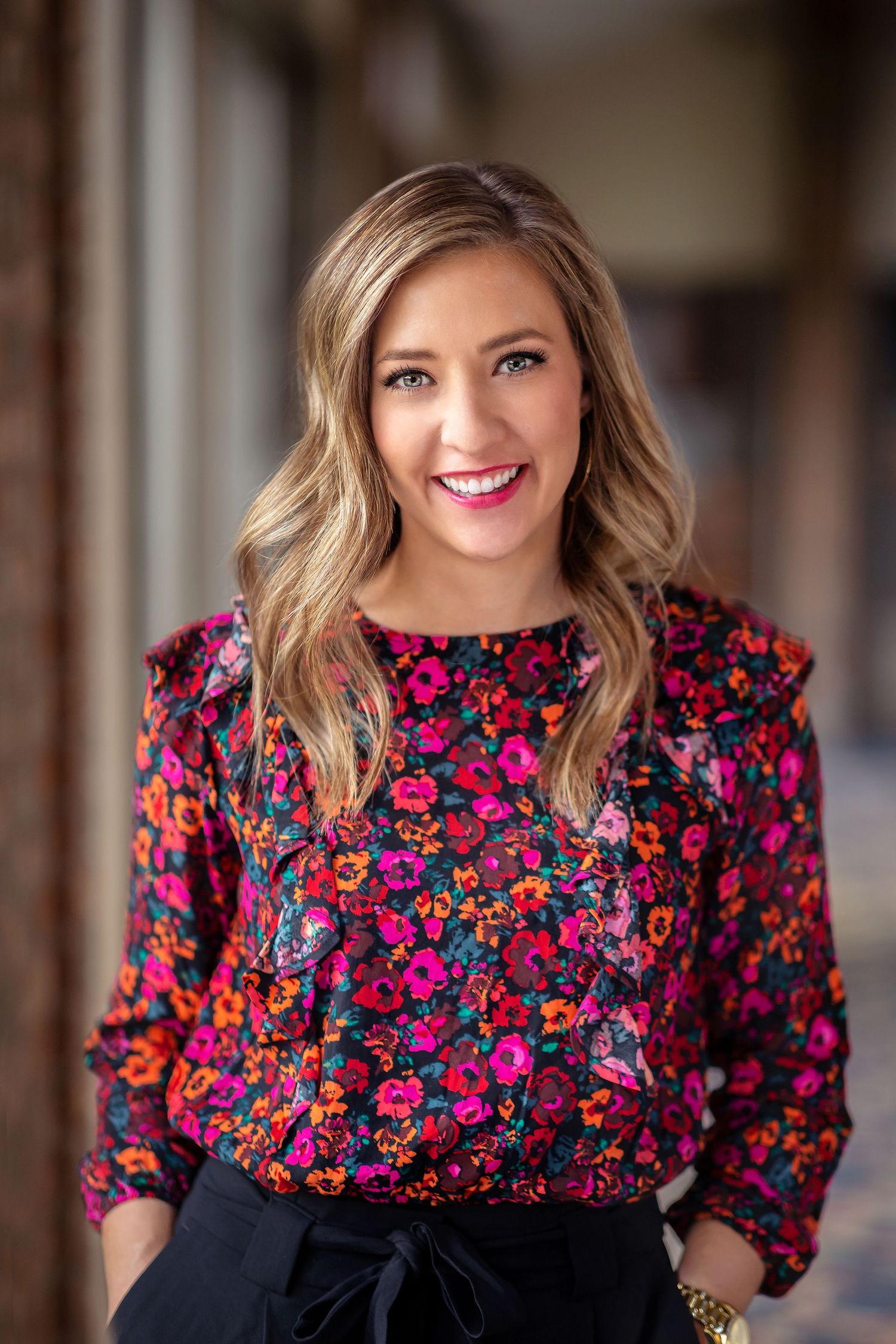 Brunette woman wearing bright floral pink shirt for corporate headshot