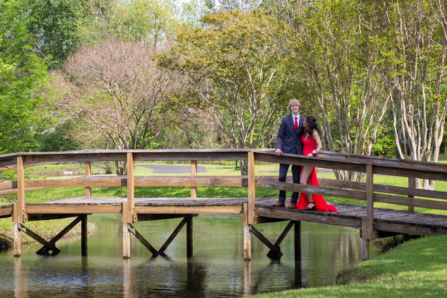 young man and young lady standing on a bridge dressed up for prom