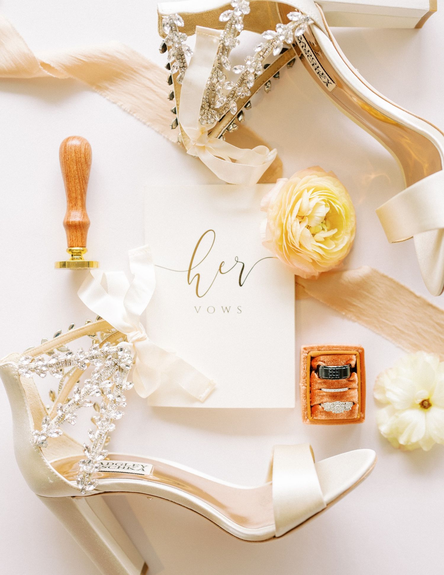 Wedding accessories including elegant heels, floral details, and vows card in soft beige and gold tones.