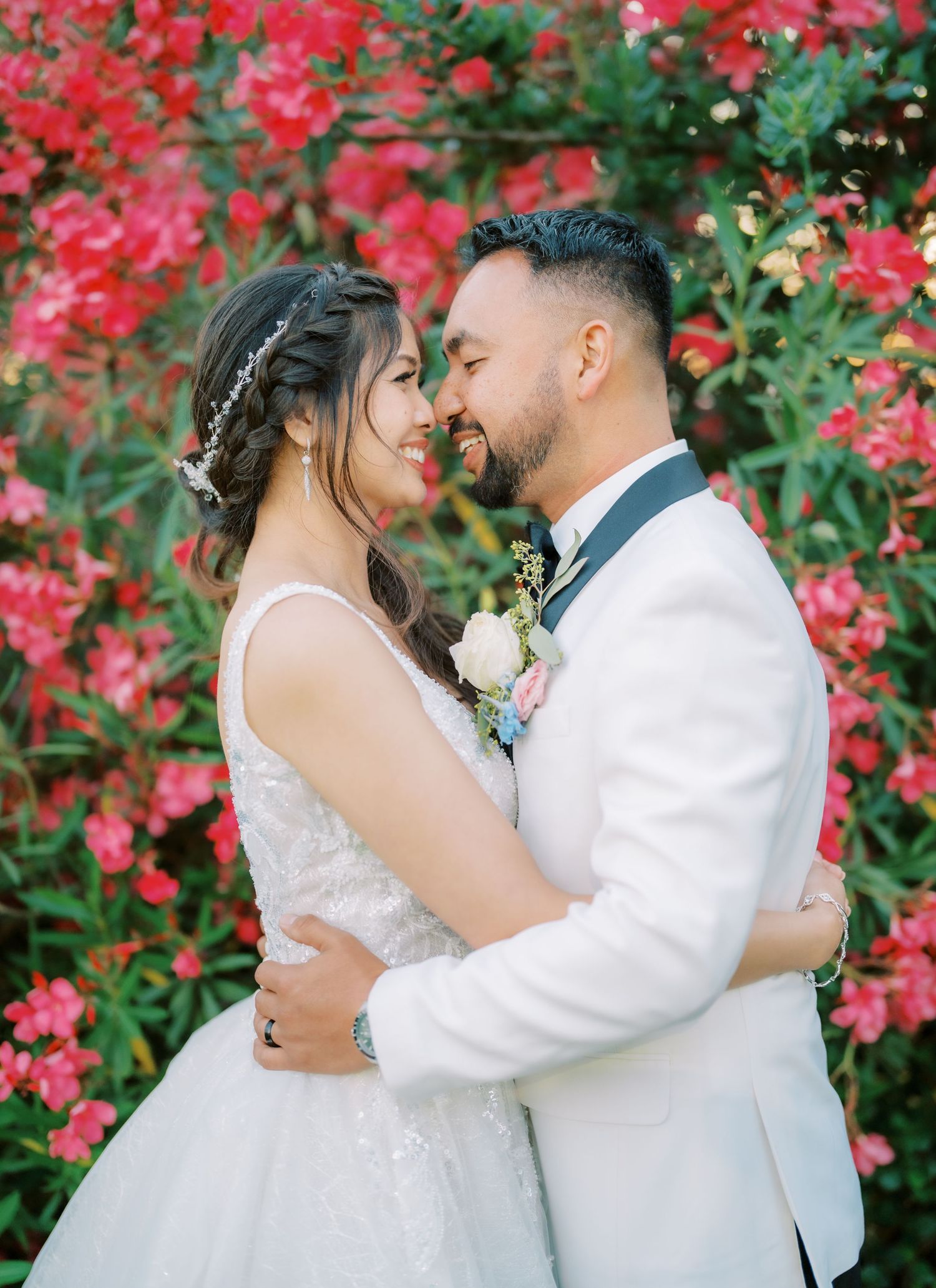 A romantic moment against vibrant red bougainvillea flowers in a garden setting.