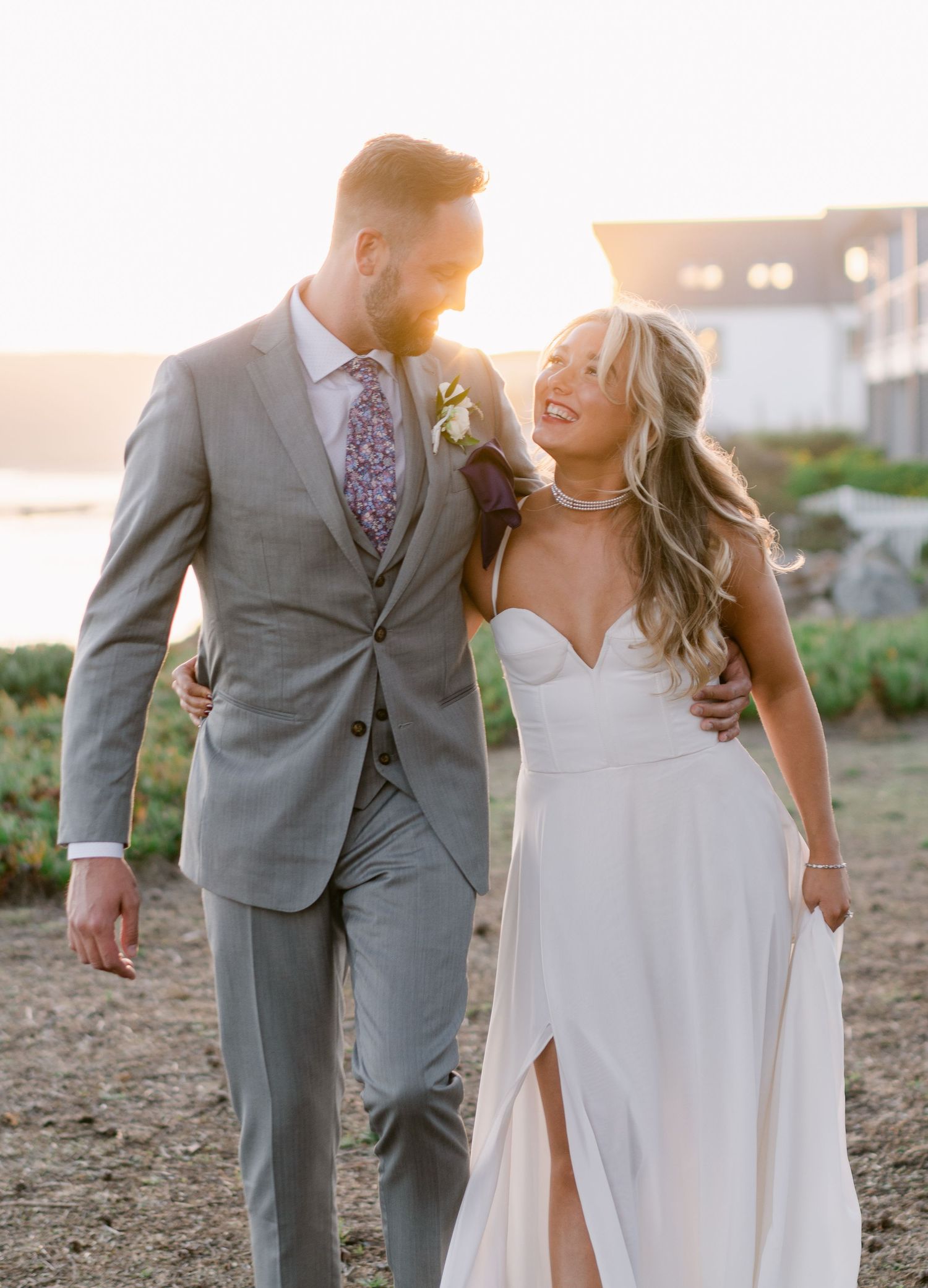 Newlyweds sharing a loving moment at sunset in formal wedding attire.