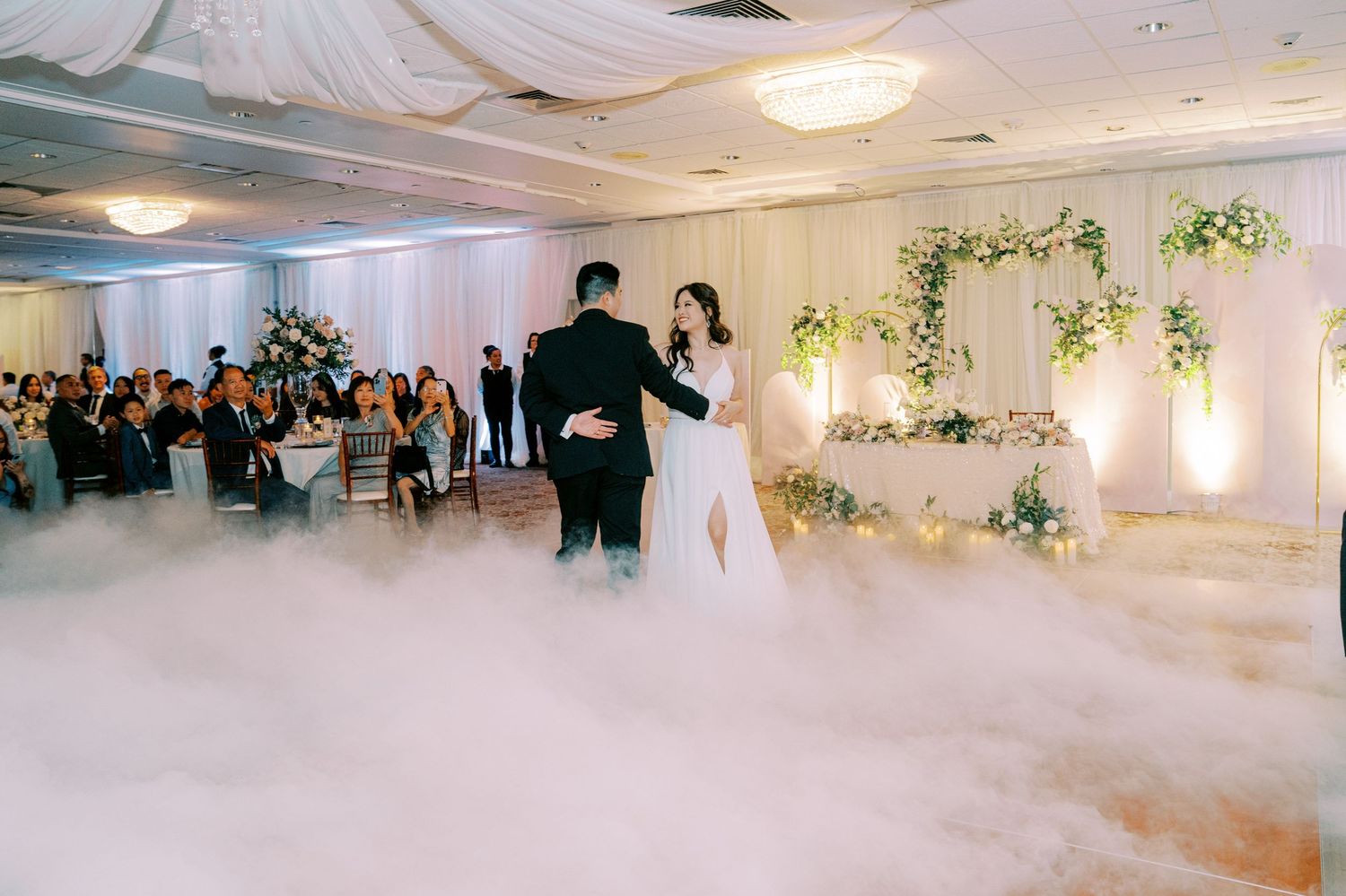 A wedding couple's first dance on a misty dance floor with romantic lighting.