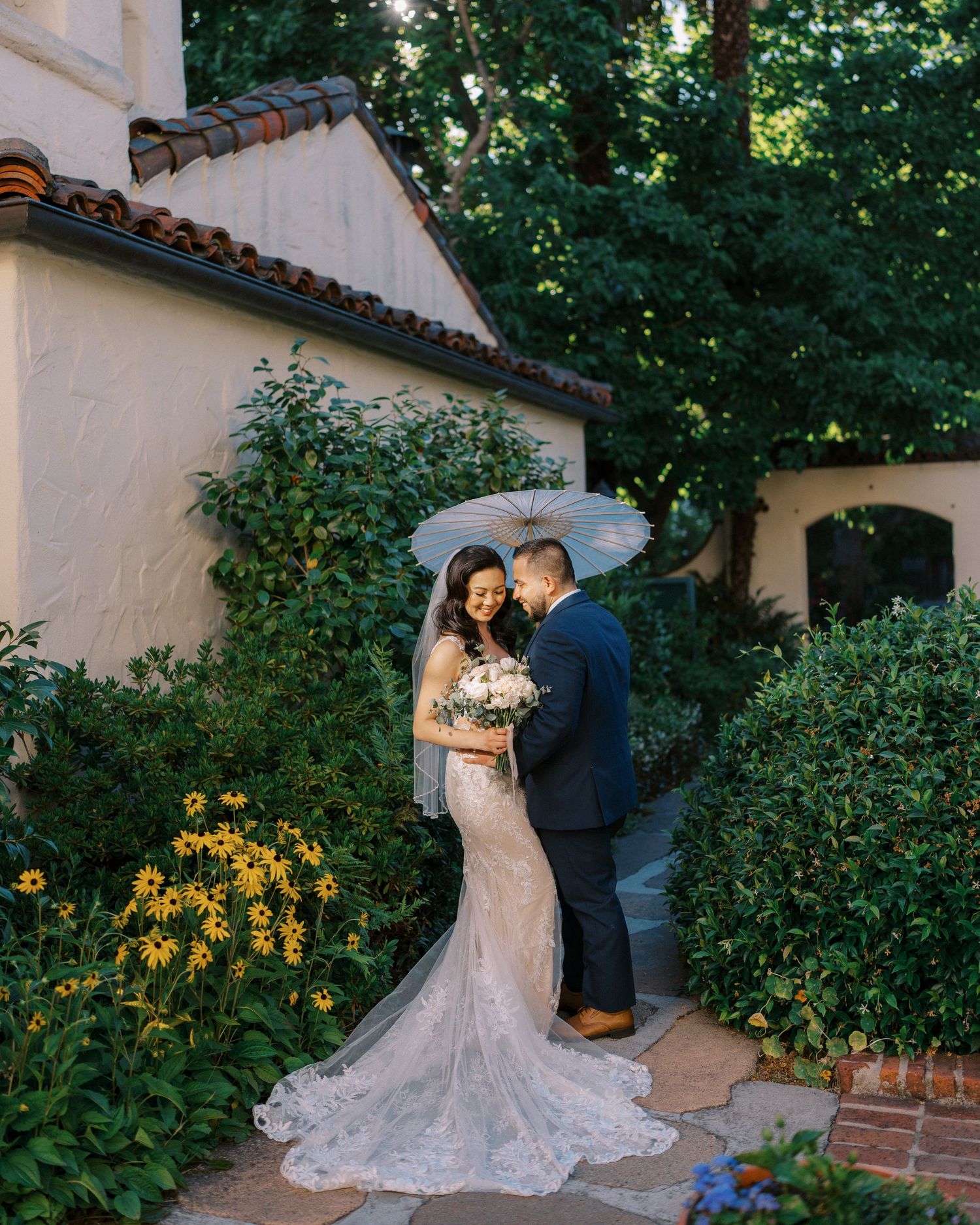 A couple shares an intimate moment in a Spanish-style courtyard with blooming yellow flowers.