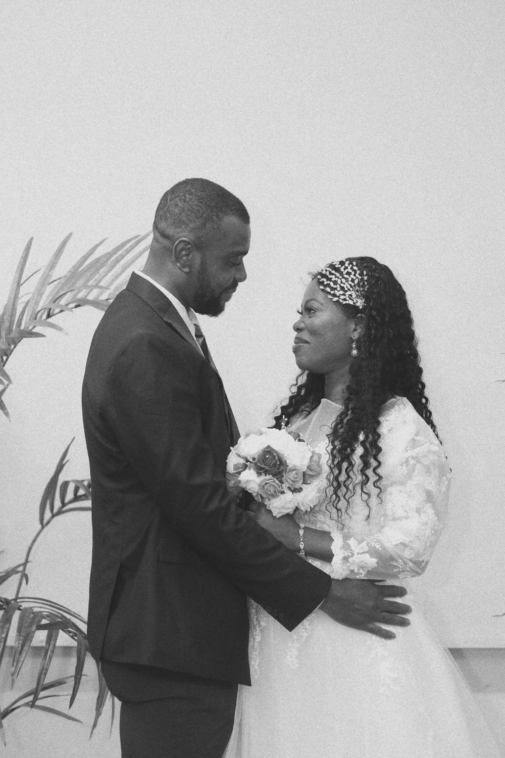 Black and white intimate wedding portrait with palm leaves in background.
