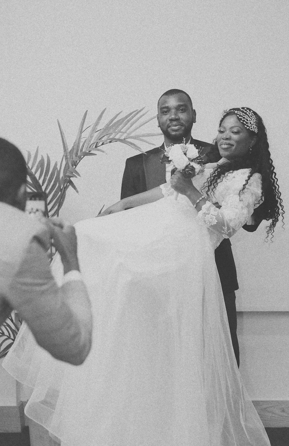 Behind-the-scenes wedding photography session with couple posing against minimal backdrop.