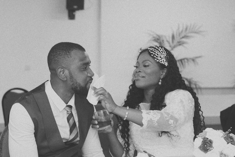 A black and white photo of a couple feeding each other during their wedding reception.