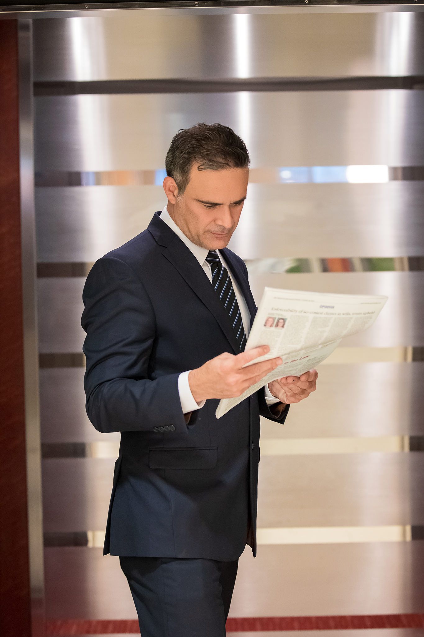 Professional in dark suit examining documents at an office desk.