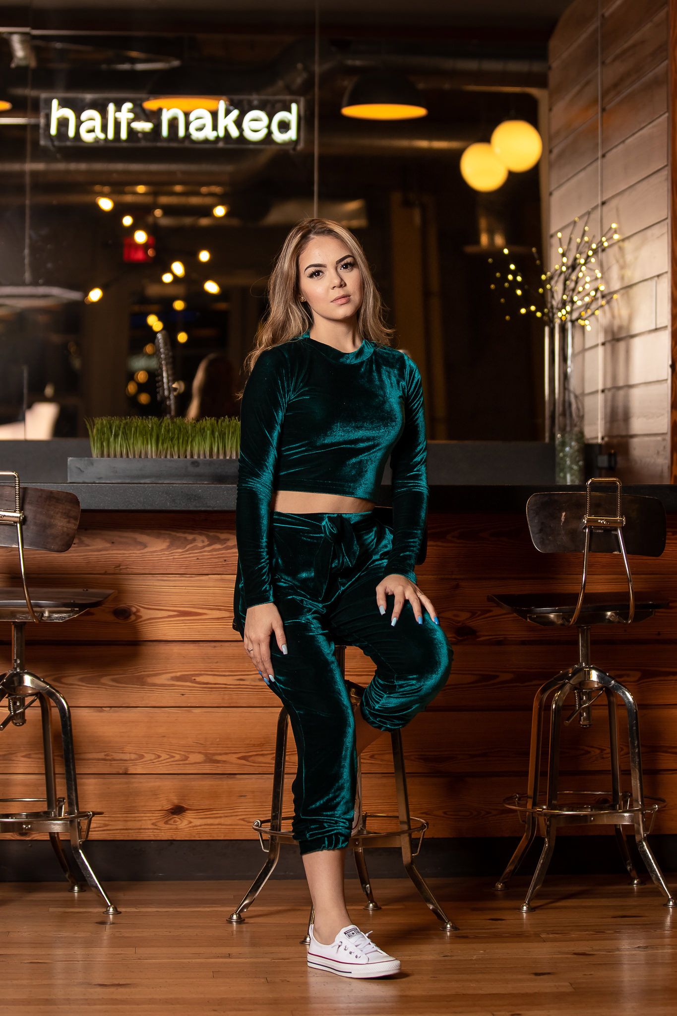 Indoor fashion shoot in velvet green outfit at restaurant with wooden furnishings.