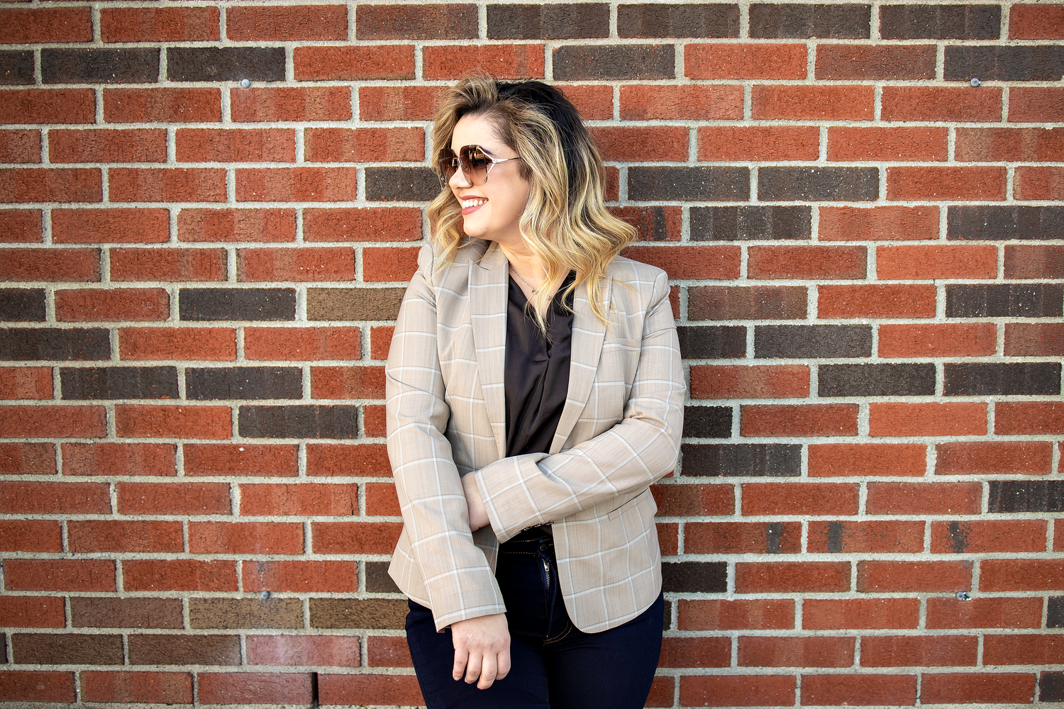 Fashion portraits against red brick wall backdrop in urban setting.