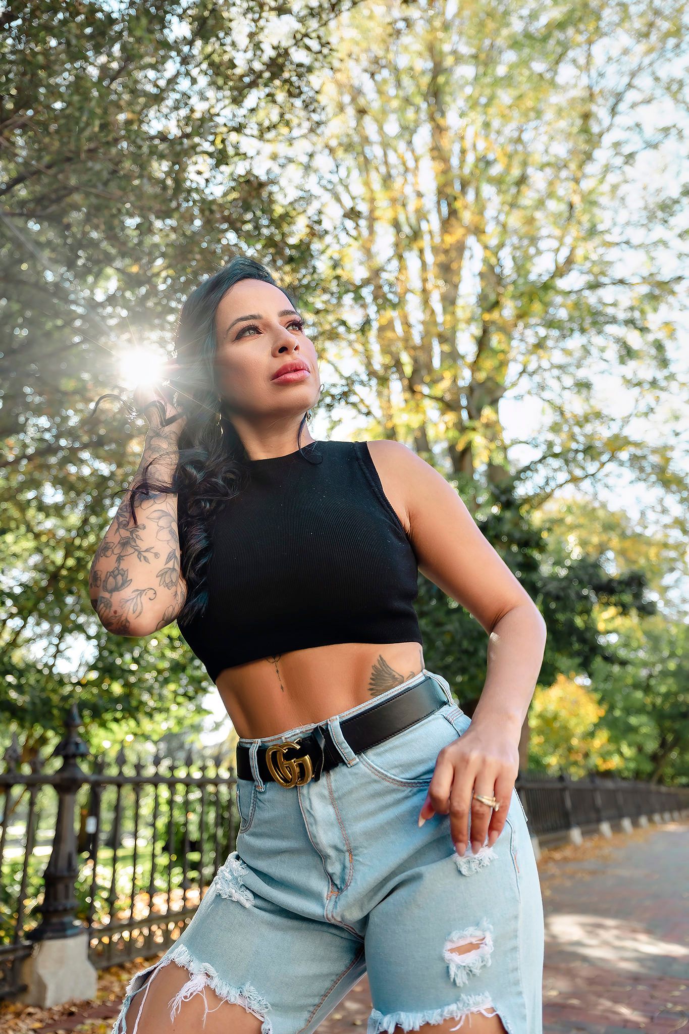Outdoor fashion portrait in casual streetwear with sunlit trees in background.