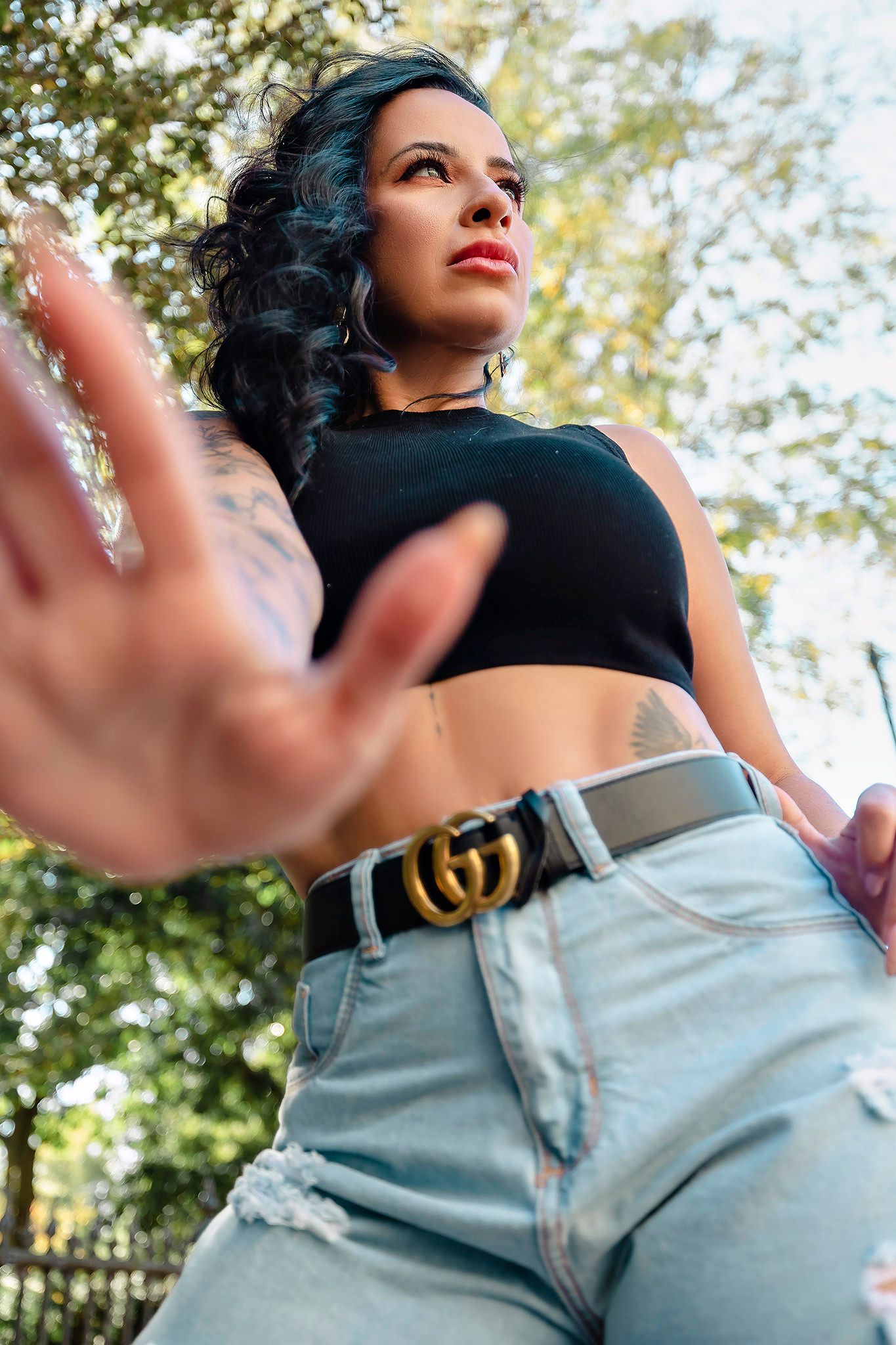 Low angle fashion shot showcasing crop top and high-waisted jeans with urban background.