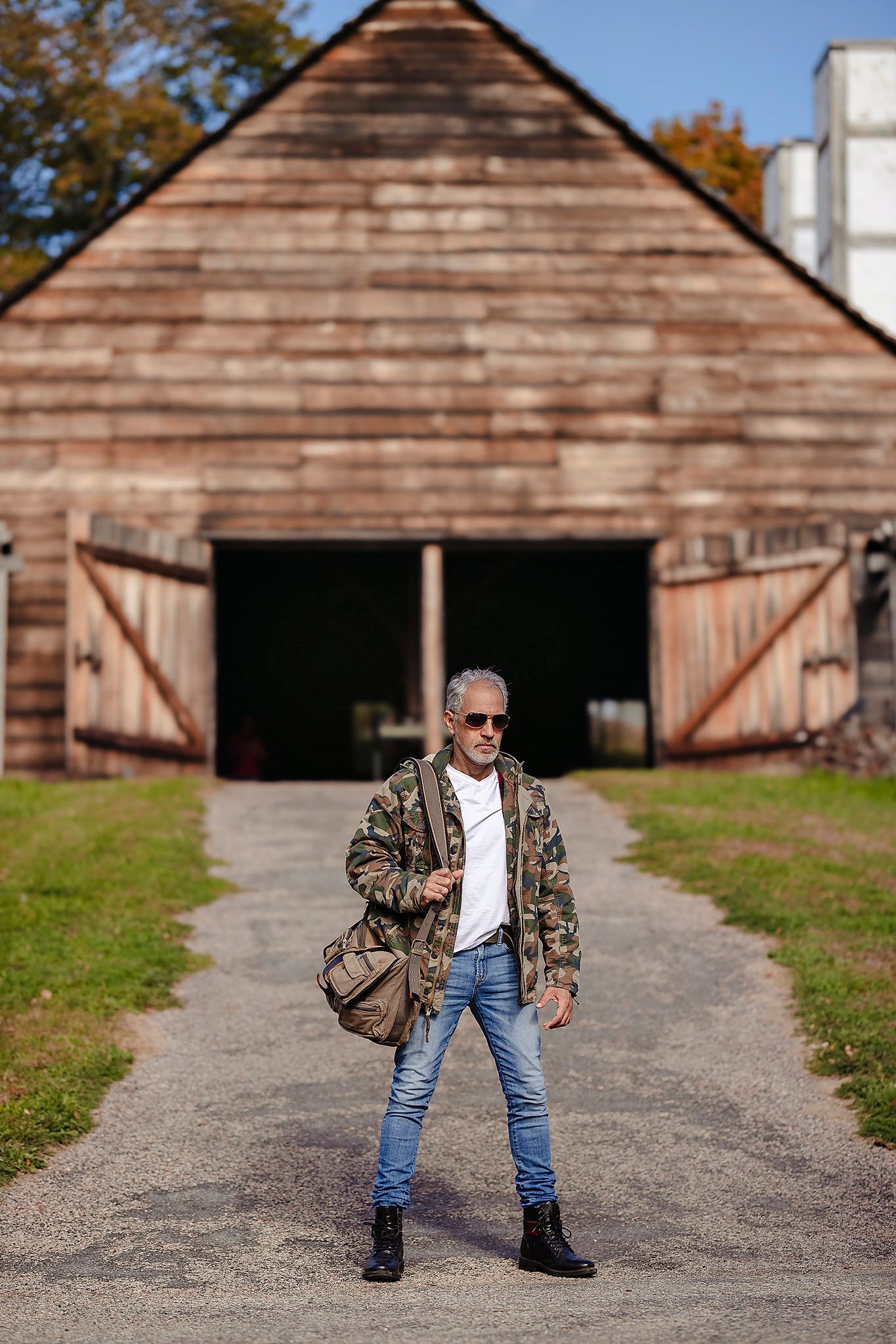 Rustic barn photo shoot with person in camouflage jacket and jeans striking dynamic poses.