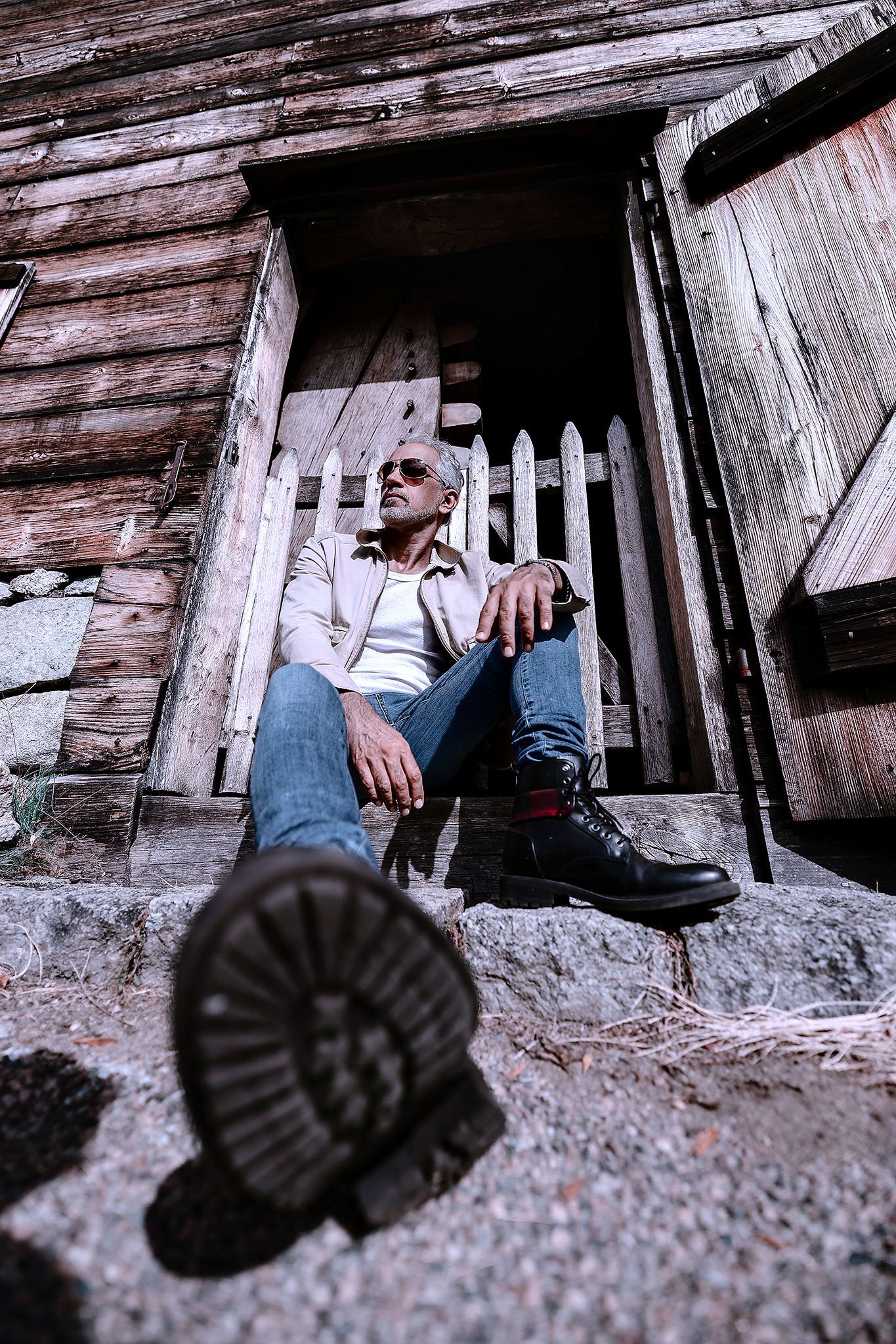 Black boots against weathered wooden boards in rustic setting.