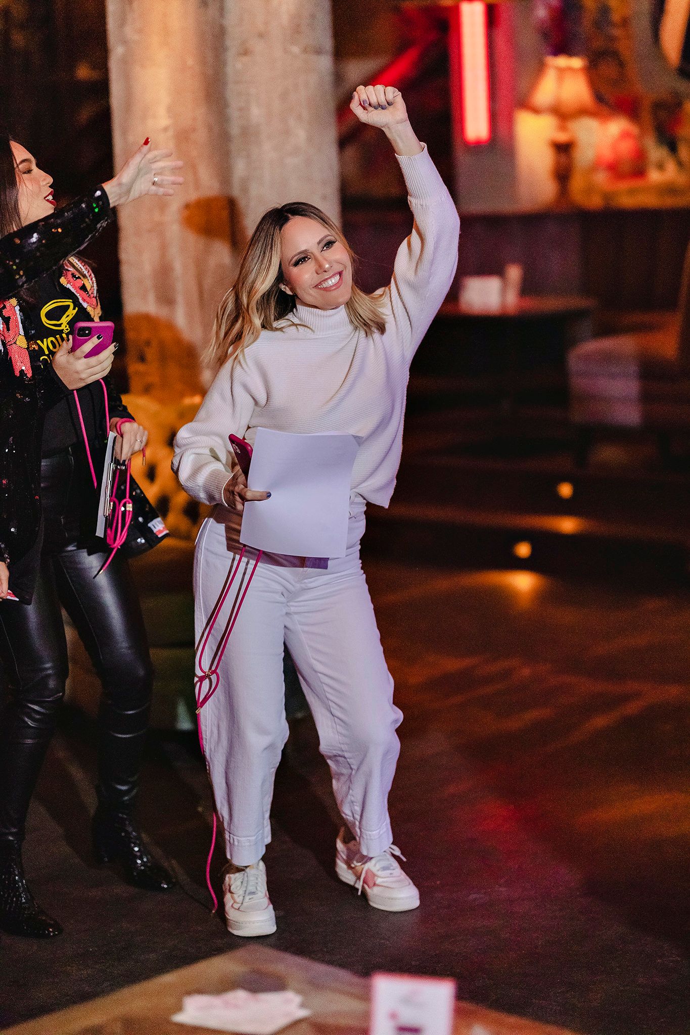 Child dancing in white outfit at night party with red lighting.