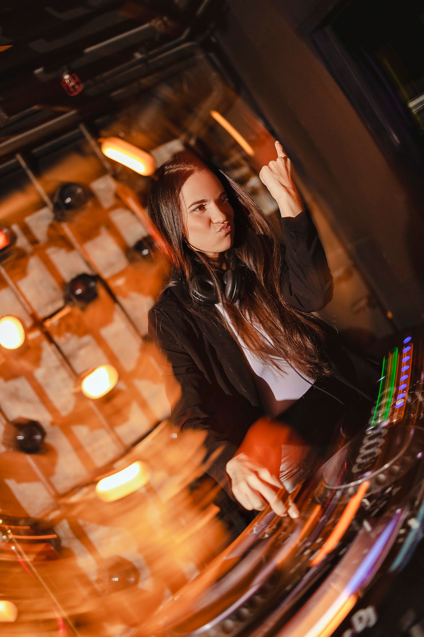 DJ performing at nightclub with warm orange lighting and equipment.