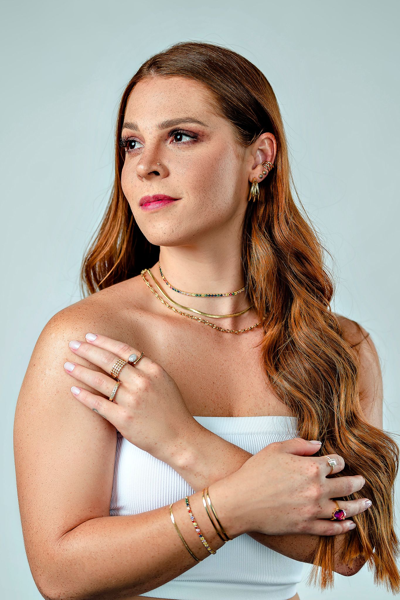 Studio portrait featuring delicate jewelry and soft makeup against mint green background.