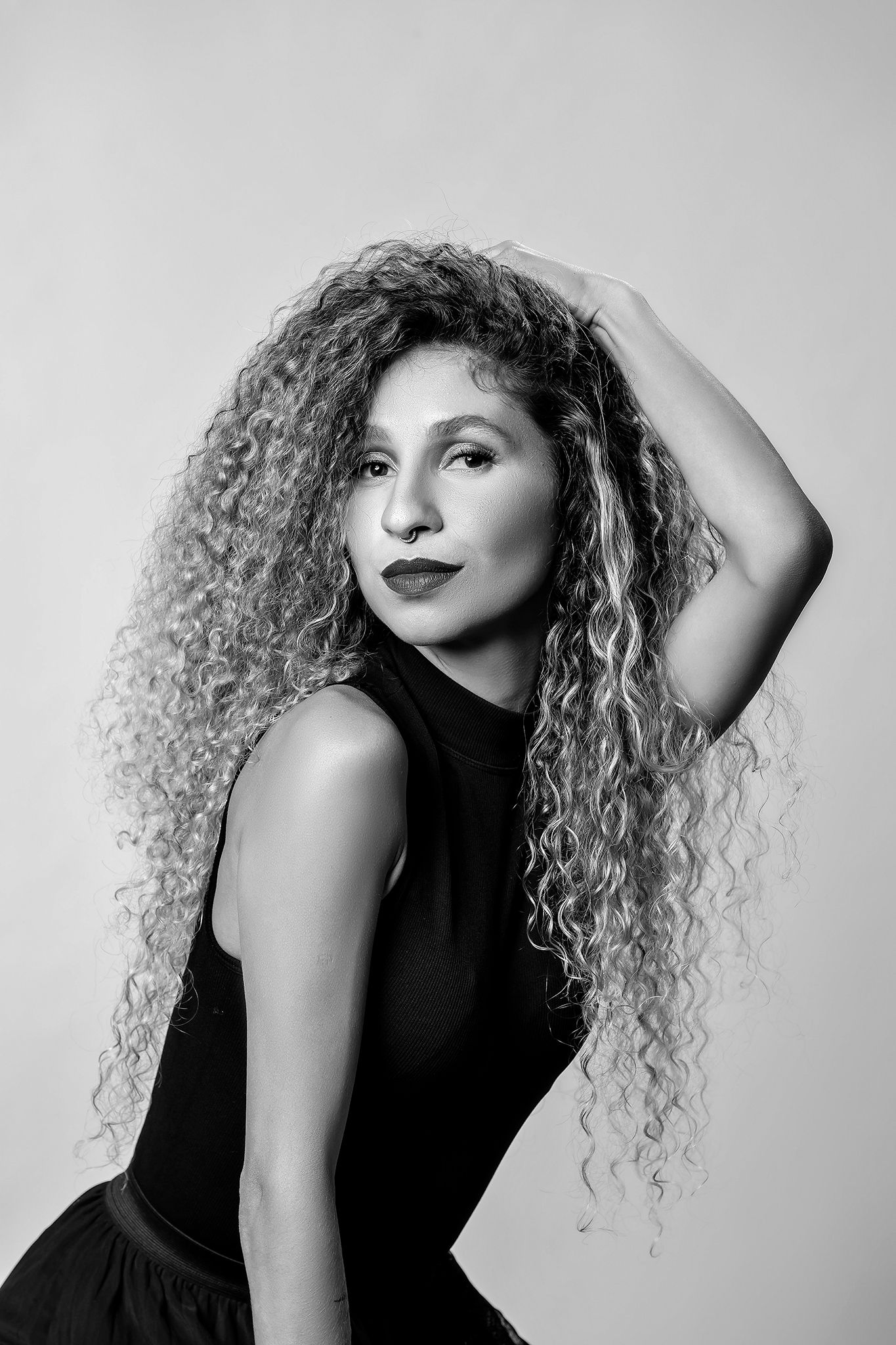 Artistic black and white portraits showcasing natural curly hair against studio backdrop.